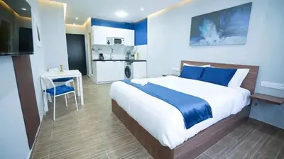 a bedroom with a large bed and a small kitchen at Luxe Bleu Studio Rabat in Rabat