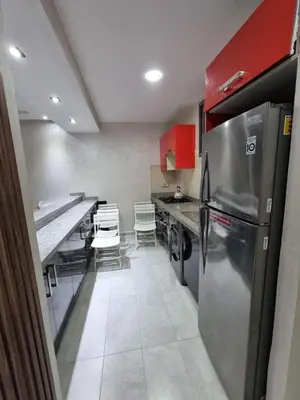 a kitchen with stainless steel appliances and red cabinets at Eden Prestige in Bouznika
