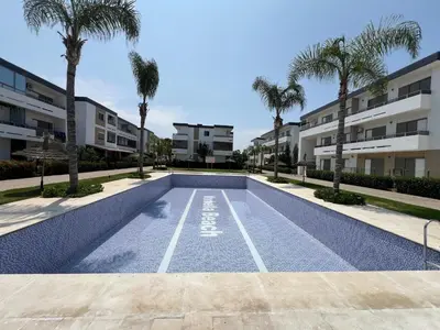 a swimming pool in a apartment complex with palm trees at Eden Prestige in Bouznika