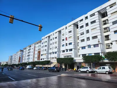 a large white building with cars parked on a street at Chambre pour une femme ou pour un couple dans un Appartement de luxe bien situé et bien équipé in Rabat