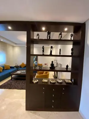 a shelf with figurines on it in a living room at Appartement meublé in Temara