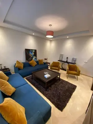 a living room with blue couches and a coffee table at Appartement meublé in Temara