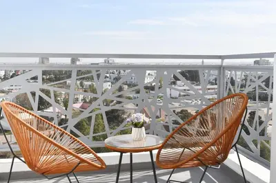 two chairs and a table with flowers on a balcony at Bright & Cozy Apt with City View in Casablanca