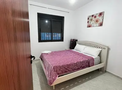 a bedroom with a bed with a purple comforter and a window at A coté hôpital M6,Proche d'Aéroport et la gare bouskoura in Bouskoura