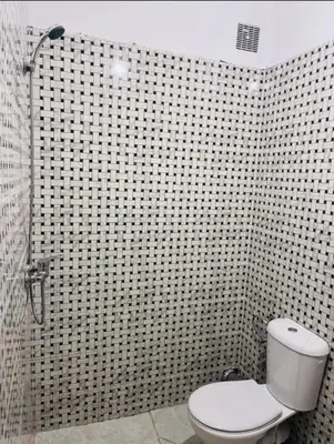 a bathroom with a toilet and a black and white tiled wall at A coté hôpital M6,Proche d'Aéroport et la gare bouskoura in Bouskoura
