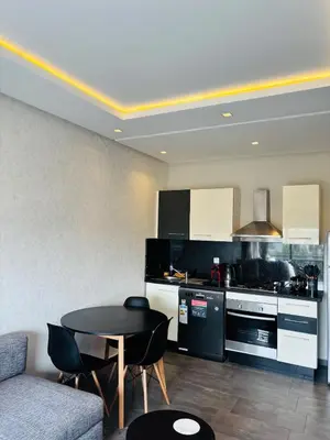 a living room with a table and a kitchen at Charming Apartment With City View in Casablanca