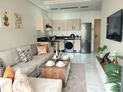 a living room with a couch and a kitchen at Cozy studio with great pool views in Aïn Harrouda