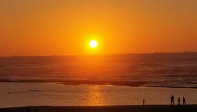 two people standing on the beach at sunset at Cozy studio with great pool views in Aïn Harrouda