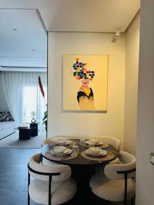 a dining room with a table with chairs and a painting at Elegant Apartment with City View in Casablanca