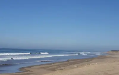 a sandy beach with waves in the ocean at Jumeirah in Sidi Rahal
