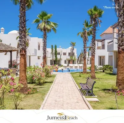 a path with palm trees and a bench in a resort at Jumeirah in Sidi Rahal