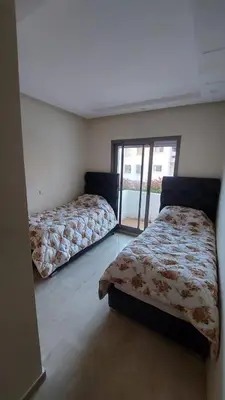 a bedroom with two beds and a sliding glass door at Jumeirah in Sidi Rahal