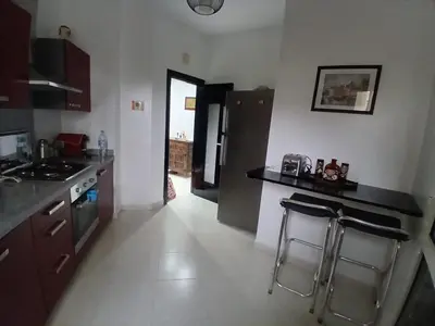 a kitchen with a counter and two stools in it at Appartement BAHIA BEACH piscine plage privée in Bouznika