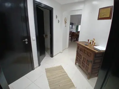 a hallway with a black door and a wooden dresser at Appartement BAHIA BEACH piscine plage privée in Bouznika