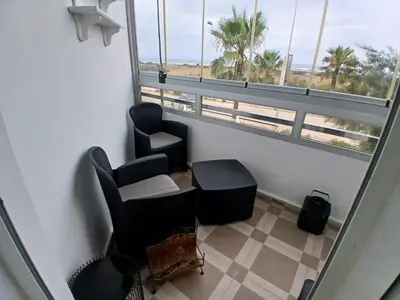 a room with chairs and a window with palm trees at Appartement BAHIA BEACH piscine plage privée in Bouznika