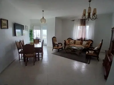 a living room with a couch and a table and chairs at Appartement BAHIA BEACH piscine plage privée in Bouznika