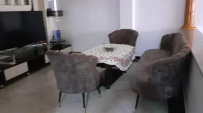 a living room with a table and chairs and a television at Le Grand Refuge des Lilas in Casablanca