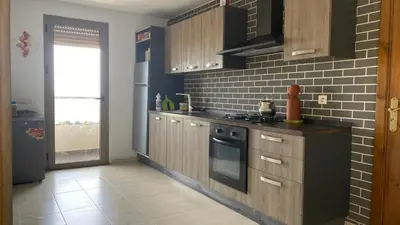 a kitchen with wooden cabinets and a black stove at Puerto Banus Appartement A4 in Mohammedia