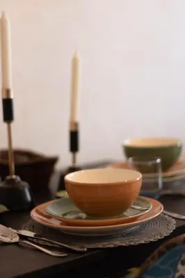 a table with bowls and plates on a table with candles at Studio chic et paisible avec piscine parc et plage in Aïn Harrouda