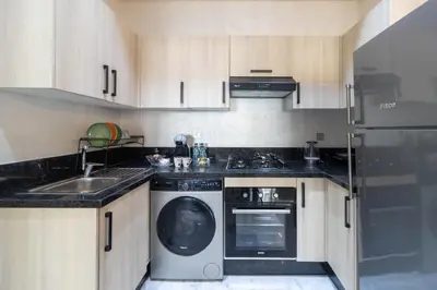 a kitchen with a washing machine and a sink at Studio chic et paisible avec piscine parc et plage in Aïn Harrouda