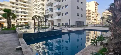 a swimming pool in front of a building at Studio chic et paisible avec piscine parc et plage in Aïn Harrouda