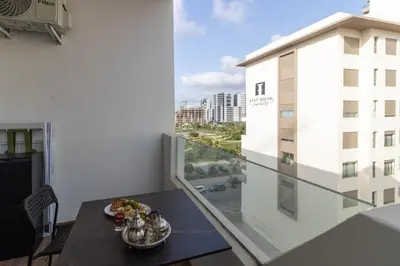 a balcony with a table and a view of a building at Studio chic et paisible avec piscine parc et plage in Aïn Harrouda