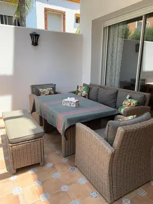 a patio with a table and wicker chairs at Villa oasis sidi rahal in Casablanca