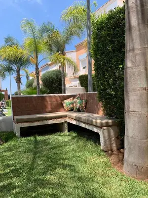 a bench sitting in the grass next to a bush at Villa oasis sidi rahal in Casablanca