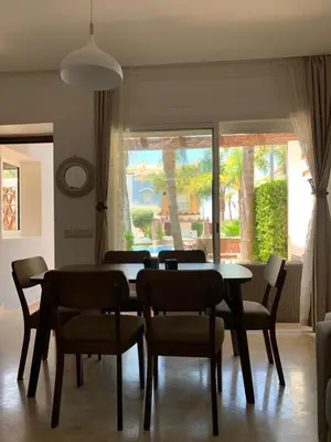 a dining room with a table and chairs and a window at Villa oasis sidi rahal in Casablanca