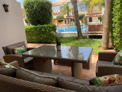 a patio with a table and chairs and a pool at Villa oasis sidi rahal in Casablanca