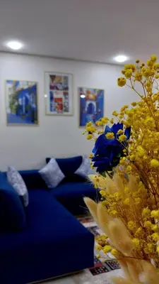 a living room with a blue couch and a flower arrangement at Studio Chefchaoun in Deroua
