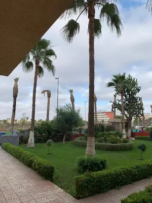 a park with palm trees in a park with a sidewalk at RESIDENCE PLAGE MANESMANe in Mohammedia