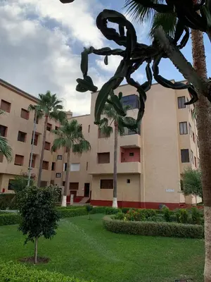 a large building with palm trees and a statue at RESIDENCE PLAGE MANESMANe in Mohammedia