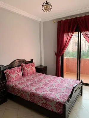 a bedroom with a bed with pink sheets and a window at RESIDENCE PLAGE MANESMANe in Mohammedia