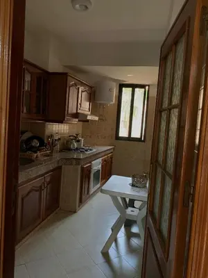 a kitchen with wooden cabinets and a table in it at RESIDENCE PLAGE MANESMANe in Mohammedia