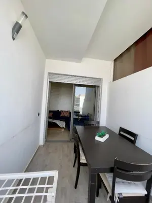 a dining room with a black table and chairs at Appartement Blanca Beach lumineux avec balcon in Sidi Rahal