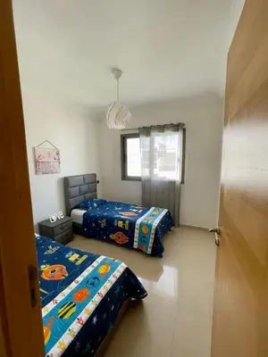 a bedroom with two beds and a window at Appartement Blanca Beach lumineux avec balcon in Sidi Rahal