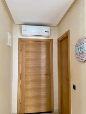 a room with a wooden door with a air conditioner on the ceiling at Appartement Blanca Beach lumineux avec balcon in Sidi Rahal