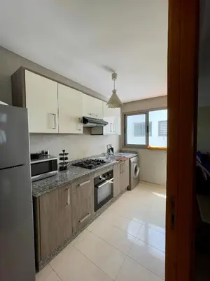 a kitchen with white cabinets and a stove top oven at Appartement Blanca Beach lumineux avec balcon in Sidi Rahal