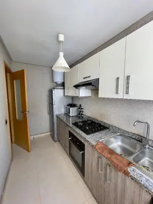 a kitchen with white cabinets and a stainless steel sink at Appartement Blanca Beach lumineux avec balcon in Sidi Rahal