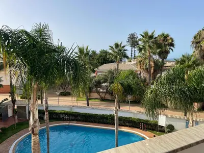 a view of a swimming pool with palm trees at Skhirat Beach Appartement in Skhirat