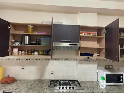 a kitchen with brown cabinets and a stove top oven at Skhirat Beach Appartement in Skhirat