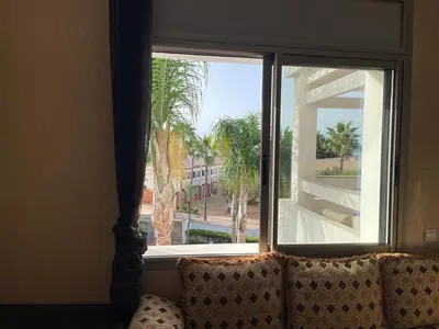 a window with a view of a palm tree at Skhirat Beach Appartement in Skhirat