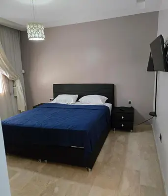 a bedroom with a bed with a blue bedspread at 2 Bedroom Apartment in Mohammedia