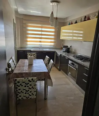 a kitchen with a table and chairs in a kitchen at 2 Bedroom Apartment in Mohammedia
