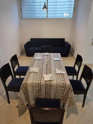 a table with chairs and a couch in a room at Seaside Artist's Villa in Temara
