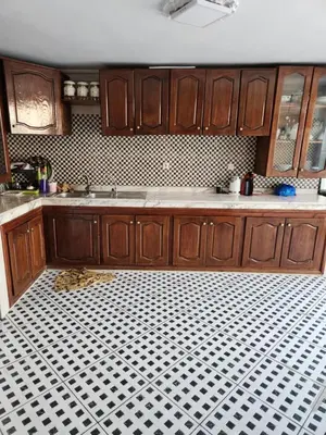 a kitchen with wooden cabinets and a black and white tile floor at Villa mouna in Mohammedia