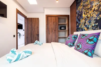a bedroom with a white bed with blue pillows at Résidence Cerezo in Maarif