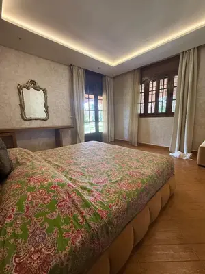 a bedroom with a large bed with a green and pink blanket at Chic home with a private pool in Dar Mouddene