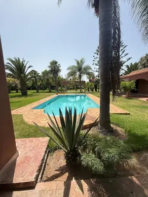 a swimming pool in a yard with a palm tree at Chic home with a private pool in Dar Mouddene